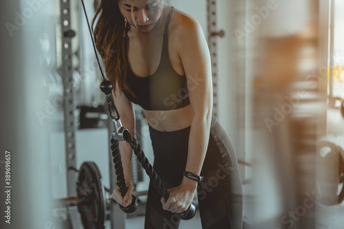 Fototapeta Naklejka Na Ścianę i Meble -  A women working out training arms in gym gaining weight pumping up muscles with dumbbells and on machines fitness concept..Fitness ,workout, gym exercise ,lifestyle and healthy concept.