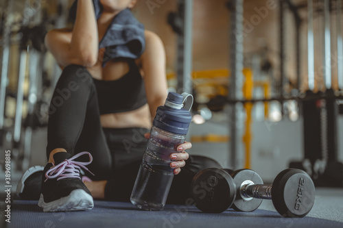 Woman exercise workout in gym fitness breaking relax after training sport with dumbbell and holdingbottle, Athlete lifestyle. Fitness ,workout, gym exercise,lifestyle and healthy concept. photo