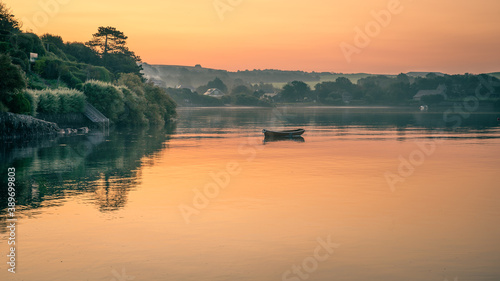Camel estuary at dawn with sunrise reflected on the calm water with boats at moorings. photo