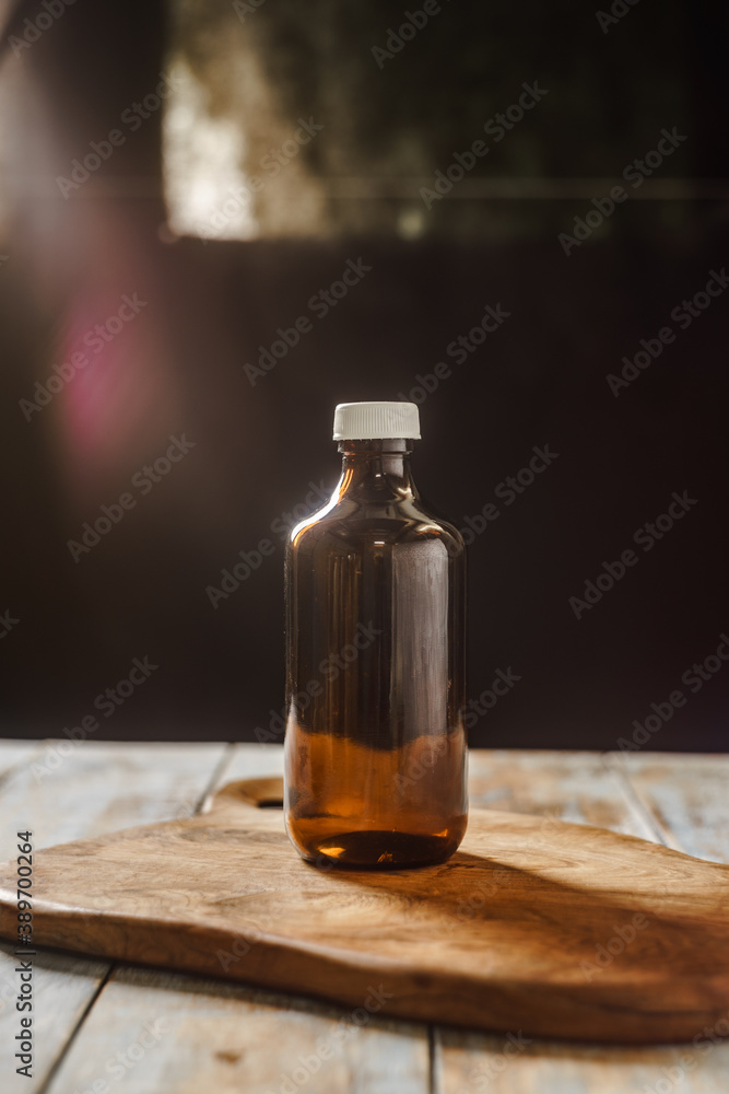 An empty bottle photographed on the wooden tray with dramatic window light & lens flare.