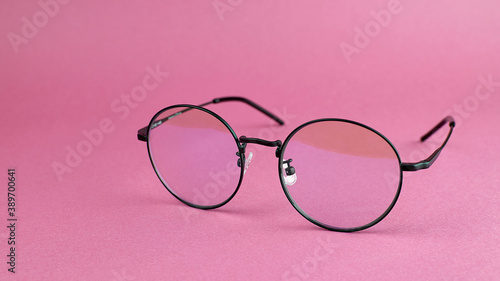 Round eyeglasses on a pink background. Fashionable round computer glasses