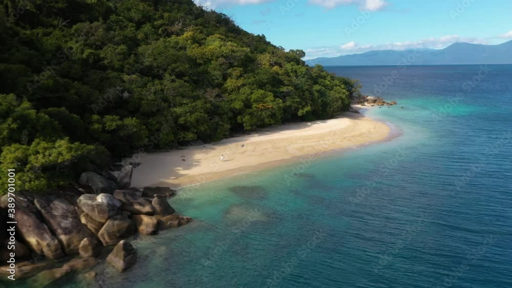 Wide rotating drone shot of woman walking on Nudey Beach on Fitzroy Island Wide rotating drone shot of woman walking on Nudey Beach on Fitzroy Island