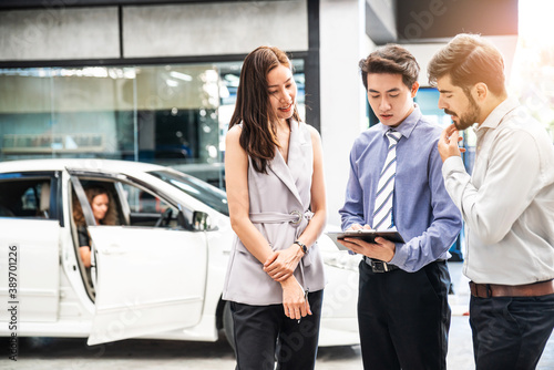 Car Dealership. The Asian Salesman (woman and man) checking the list with the middle east customer before hand over. Automotive Leasing and Dealing Business. International Business.