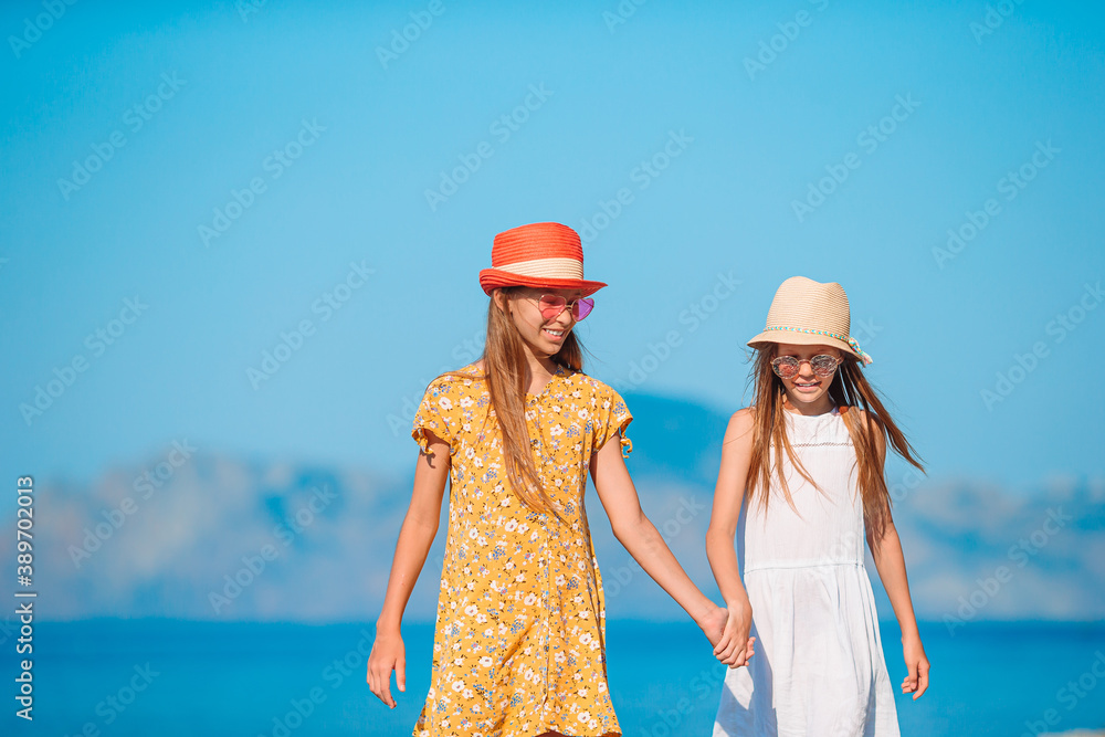Little happy funny girls have a lot of fun at tropical beach playing together