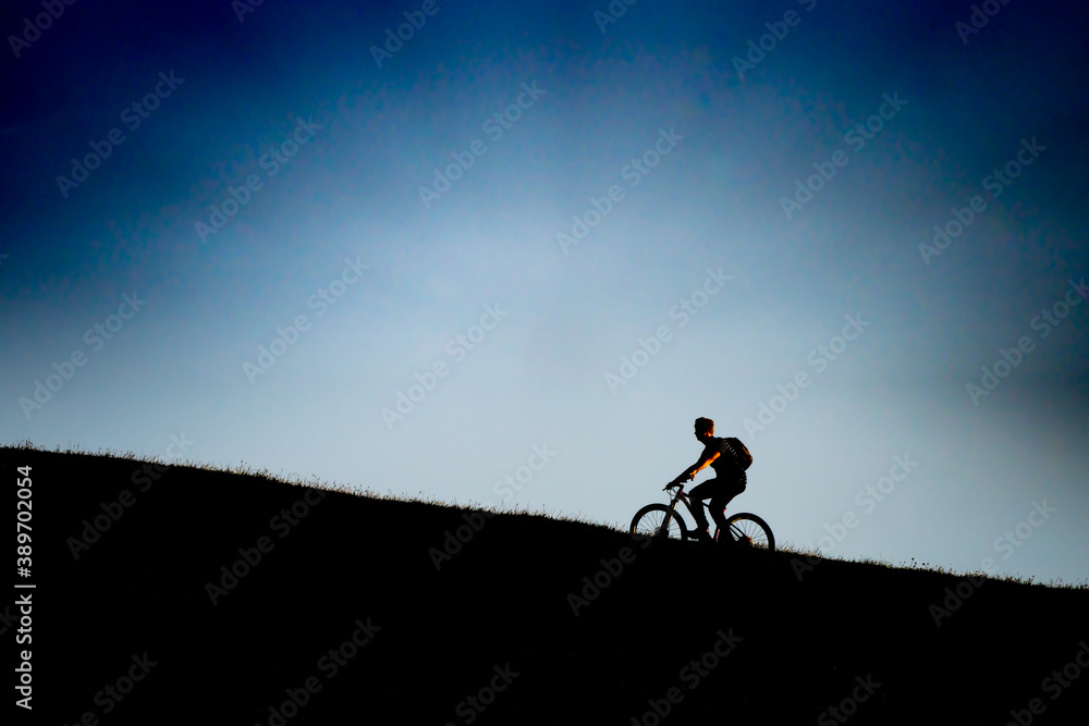 Cyclist Going Uphill At Sunset, Silhouette