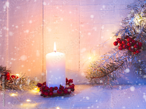 Fir branches, candle and Christmas decorations on the old wooden table. Focus on candle flame