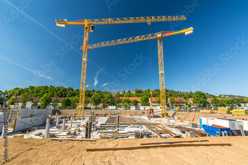 Construction site with large excavation and cranes on a sunny day