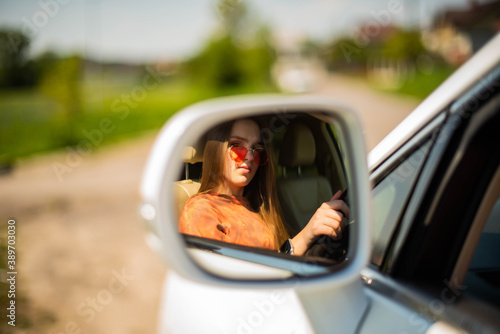 Close up portrait of pleasant looking female girl with, sits on driver`s seat, enjoys music. People, driving, transport concept.Portrait of beautiful young woman in the new car - outdoors © MartaKlos