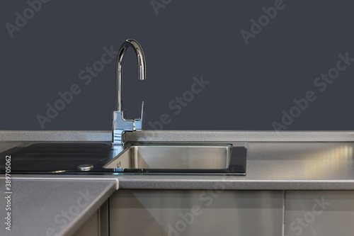 Modern design kitchen sink in a modern residential building. Modern shiny kitchen sink with faucet and mockup in the background.