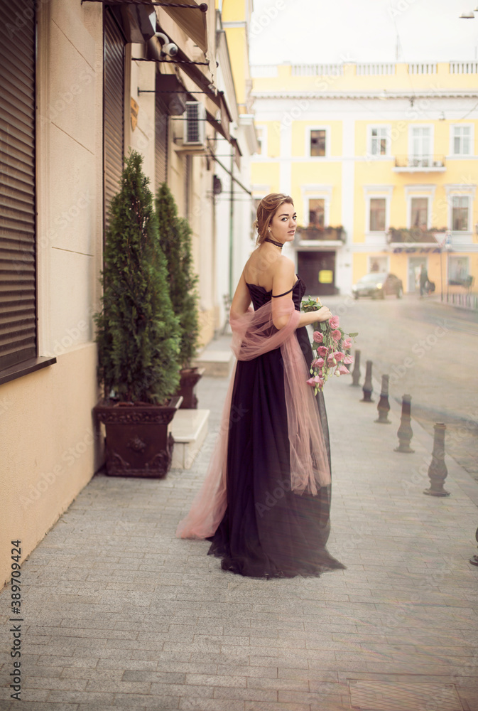 
A girl in a long black dress walks through the old city