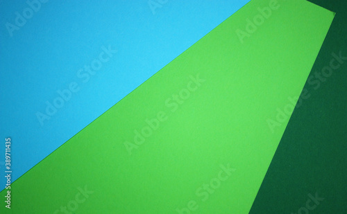 Colorful paper as a triple background. Blue, light and dark green. Vibrant backdrop. Copy space for text. Top view. Flat lay. Template.
