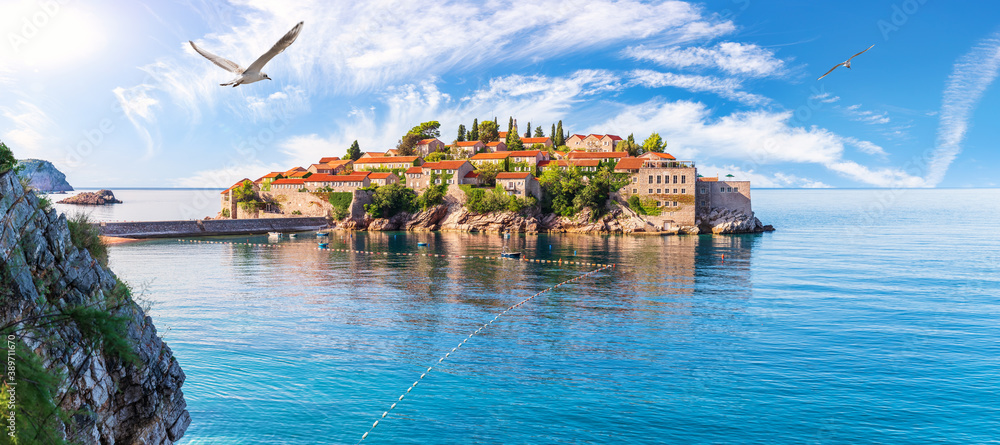 Seagull flies by Sveti Stefan island, wonderful panorama from the rock, Budva riviera, Montenegro