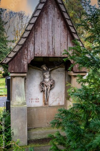 alter Grabstein mit einer Überdachung aus Holz und einer Jesusfigur 