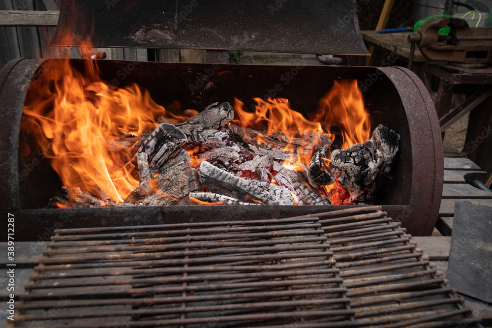 Close up of old rusty barbecue grill with burning wood and grill grates Close up of old rusty barbecue grill with burning wood and grill grates
