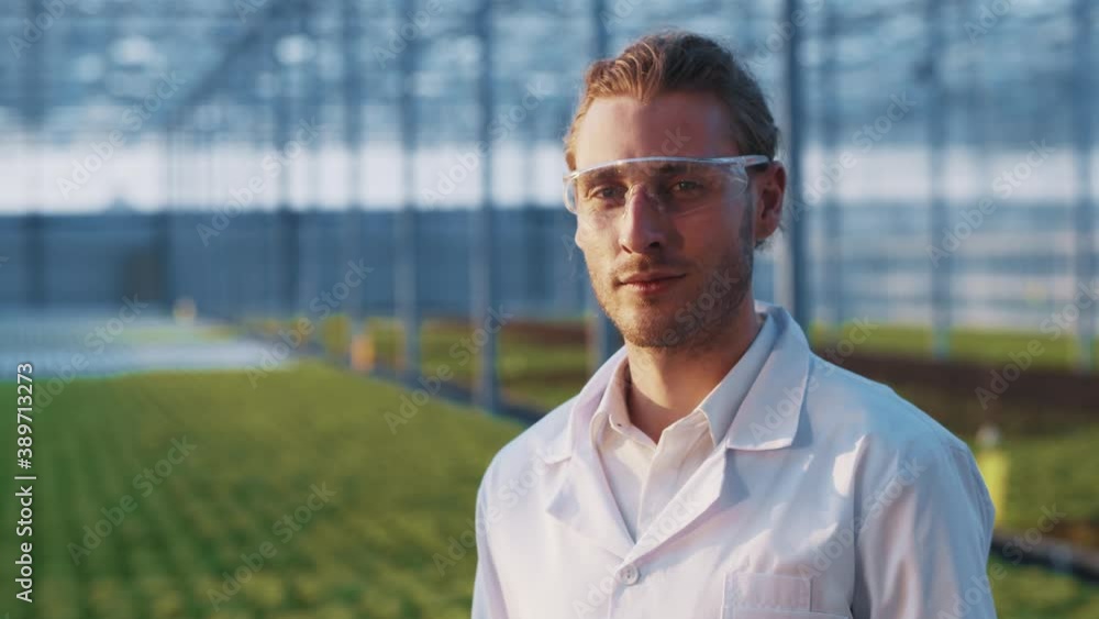 Portrait of positive caucasian young farm worker inside greenery. Young specialist professional farming scientist smiling into camera. Greenhouse people. Portrait of positive caucasian young farm worker inside greenery. Young specialist professional farming scientist smiling into camera. Greenhouse people.