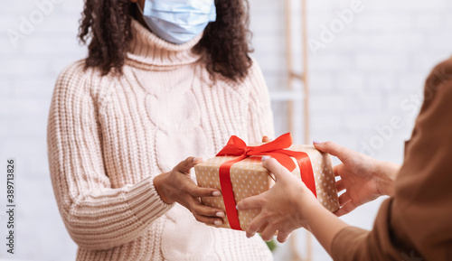Black woman wearing medical mask, receiving gift box