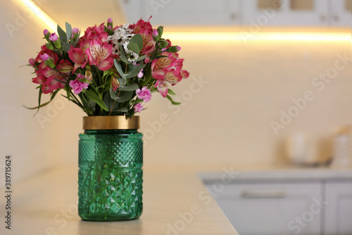 Vase with beautiful alstroemeria on countertop in kitchen, space for text. Interior design