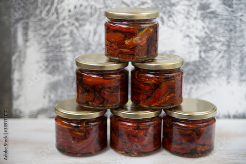 Sun-dried tomatoes are laid out in jars stand on the table isolated.