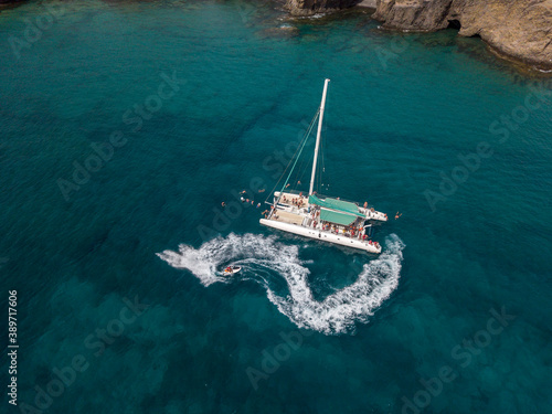 Aerial view of a catamaran with person on board and in the sea, swimming near the coasts of the island of Lanzarote, Canary, Spain. Jet ski performing in the sea 