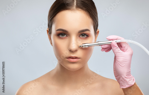 Beautiful girl with clean fresh skin.Cosmetologist makes procedure microdermabrasion on the face against acne and blackheads on the nose. Women's cosmetology in the beauty salon.