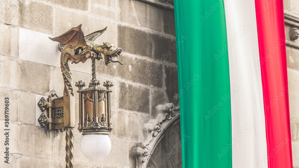 Lámpara de hierro en forma de dragón en un edificio del Centro Histórico de la Ciudad de México con  bandera mexicana colgante.