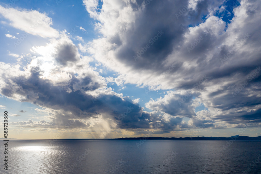 Kea, Tzia island, destination Greece. Silver sunbeams on the sea through clouds background.