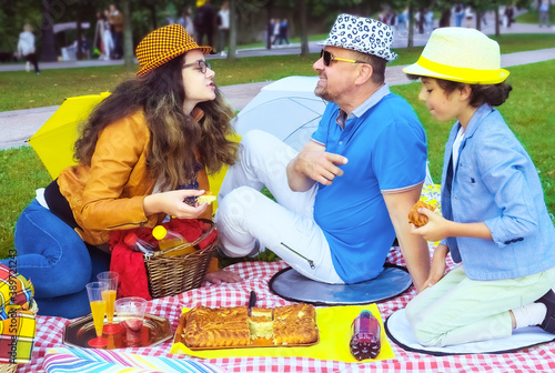 dad, teenage daughter and little son on the picnic in the park outdoors. The concept of summer holiday. father's, baby's day. Family spending time together on nature. Family look