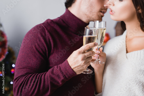 cropped view of glasses with champagne in hands of couple on blurred background