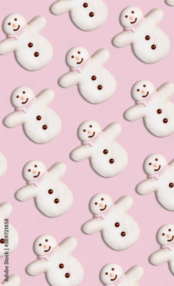 Vertical pattern of Christmas cookies in the shape of snowman decorated with icing sugar and fondant on a pink background