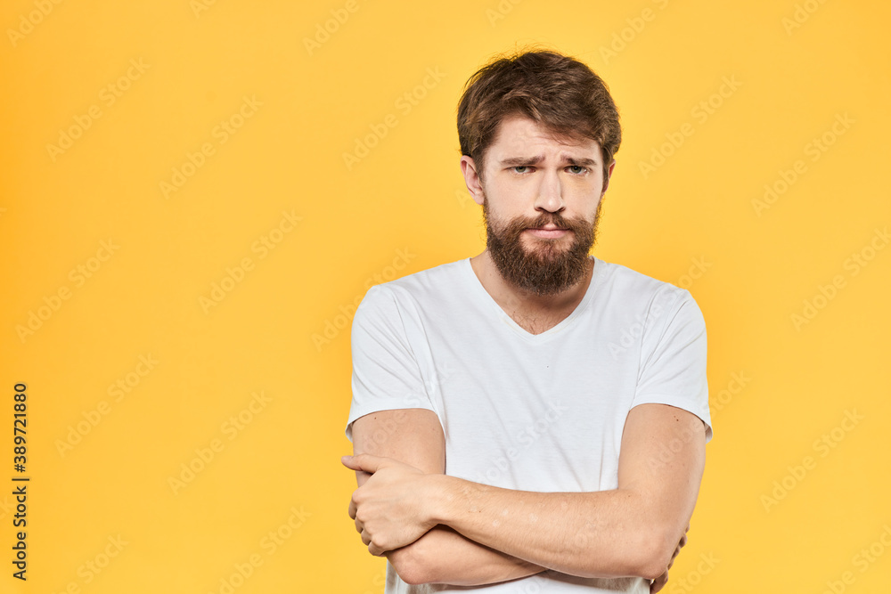 Bearded man emotions gestures with hands facial expression white t-shirt yellow background Bearded man emotions gestures with hands facial expression white t-shirt yellow background