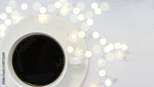 on a light background among bokeh white Cup on a saucer with black coffee