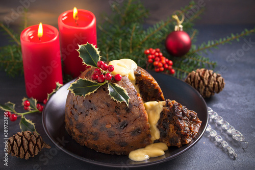 Richly spiced Christmas pudding cake with custard and Christmas decorations