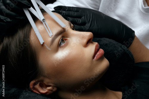 Beautician in gloves making measuring of eyebrows photo