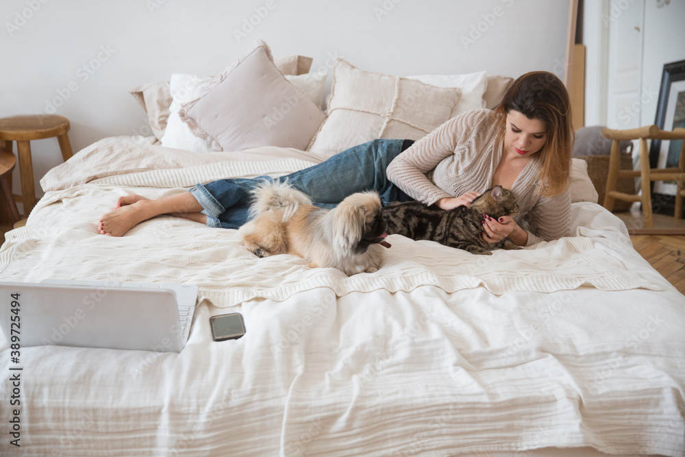 Woman lying on the bed with her pets little dog and cat
Woman lying on the bed with her pets little dog and cat