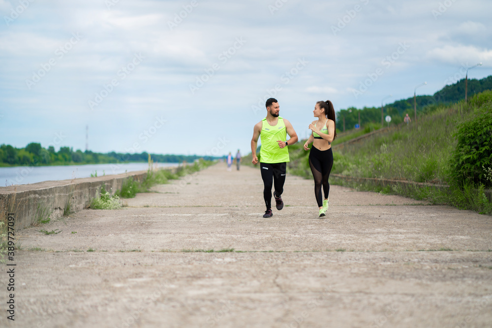 Running young couple in stylish sportswear outdoor in cloudy weather, healthy active lifestyle Running young couple in stylish sportswear outdoor in cloudy weather, healthy active lifestyle