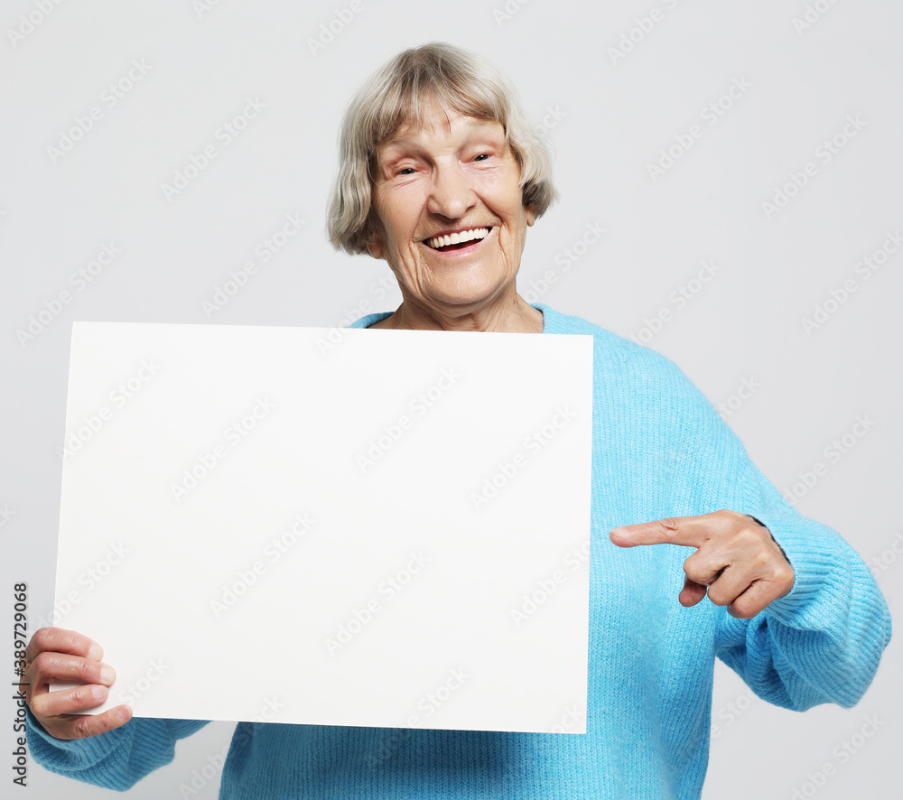 Portrait of handsome expressive grandmother in light blue sweater. Indoor,studio shot, isolated on gray background Portrait of handsome expressive grandmother in light blue sweater. Indoor,studio shot, isolated on gray background