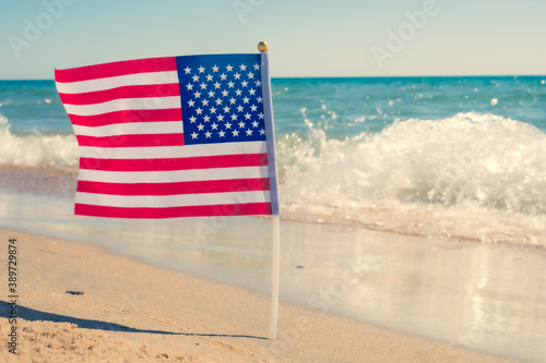 USA patriotic background with American flag on a sandy beach.