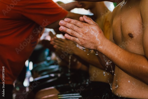 Thai man shower by a parent during a Buddhist ordination ceremony. Preparation for new Thai monk.