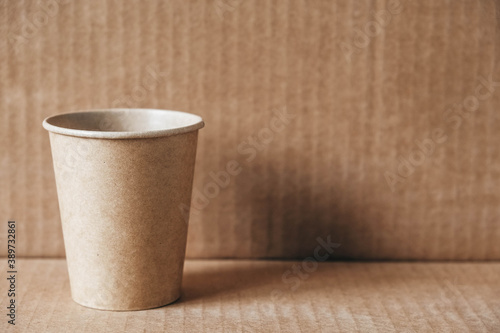 Disposable paper cup on kraft paper background. Eco friendly disposable tableware. Zero waste concept. Copy, empty space for text
