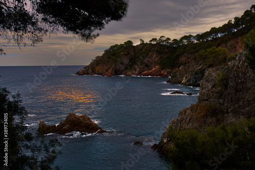 Seascape of a rocky coast that juts out into the Mediterranean Sea, at sunset, with a cloudy sky