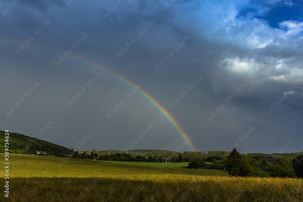 Double rainbow in countryside. Beautiful intense rainbow colors in rainy day.Weather forecast.Fall rural landscape with rainbow over dark dramatic stormy sky.Freedom happiness concept Double rainbow in countryside. Beautiful intense rainbow colors in rainy day.Weather forecast.Fall rural landscape with rainbow over dark dramatic stormy sky.Freedom happiness concept