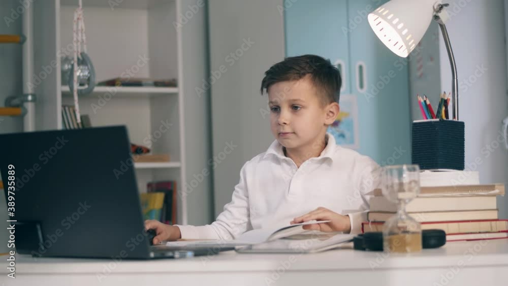 Little schoolboy studying remotely using his tablet and laptop Little schoolboy studying remotely using his tablet and laptop