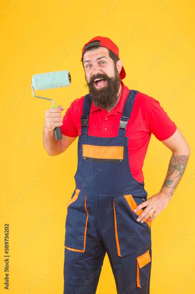 surprised bearded male painter worker in boiler suit uniform using paint roller tool for painting wall into yellow color, building surprised bearded male painter worker in boiler suit uniform using paint roller tool for painting wall into yellow color, building