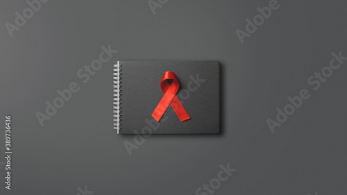red AIDS ribbon on black notebook
