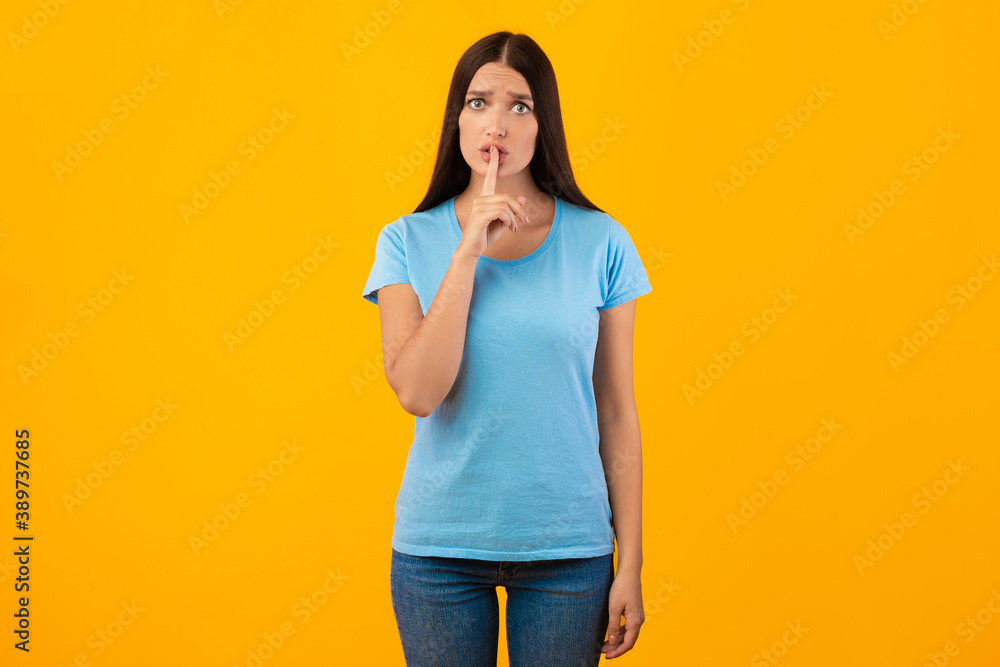 Woman putting finger on his lips, making silence gesture Woman putting finger on his lips, making silence gesture