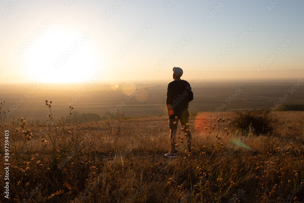 a young man stands and admires the sunrise