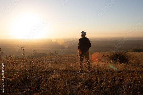 a young man stands and admires the sunrise