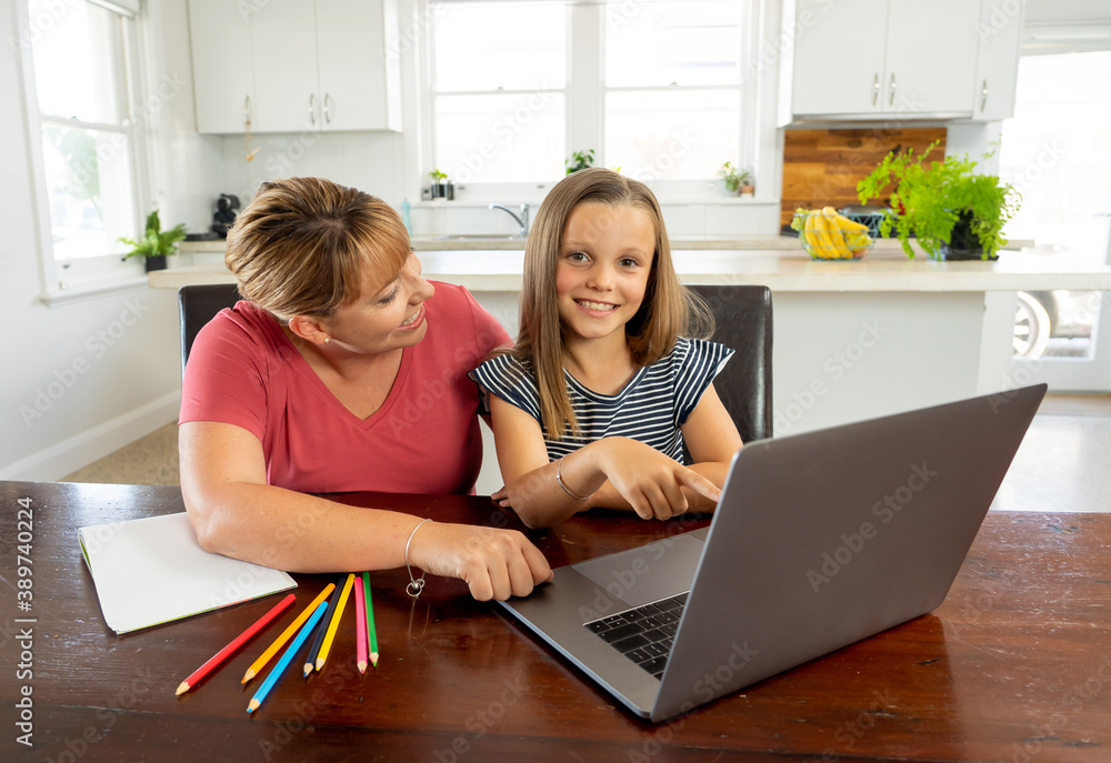 Mother and happy daughter studying at home during coronavirus self isolation and school closures Mother and happy daughter studying at home during coronavirus self isolation and school closures