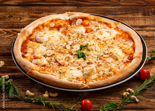 Pizza with garlic slices and spices on wooden background