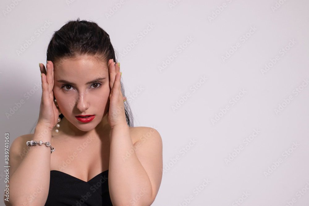 emotional portrait of attractive brunette in black top with white pearl earrings on white background. emotional portrait of attractive brunette in black top with white pearl earrings on white background.
